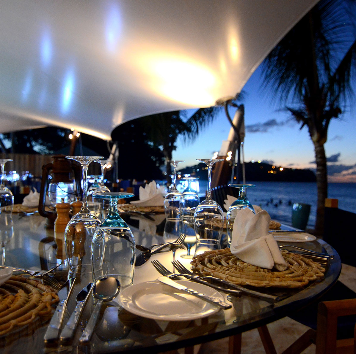 Beach club tables adorned with glassware, cutlery and napiery